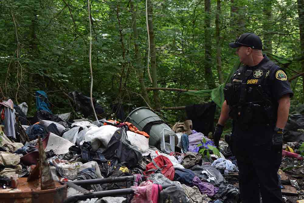 garbage debris homeless encampment officer standing